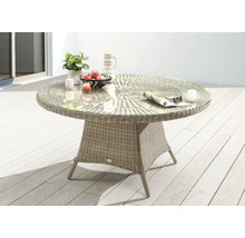 Table de jardin ronde avec plateau en verre et socle tressé sur une terrasse.