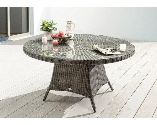 Runder Gartentisch mit Glasplatte und Rattanoptik auf einer Terrasse.