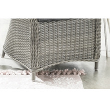 Detailaufnahme eines Gartenstuhls aus Rattan auf einem gemusterten Teppich