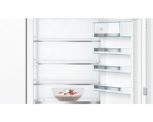 Vue intérieure d'un réfrigérateur avec des étagères en verre et un saladier de fraises