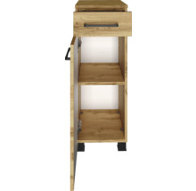 Meuble bas étroit aspect chêne avec un tiroir, une porte ouverte et une étagère, poignées et pieds noirs.