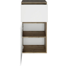 Meuble bas de salle de bains aspect chêne avec un tiroir blanc et une porte ouverte, deux étagères.