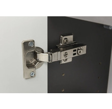 Charnière invisible en métal montée sur une porte d'armoire et un corps de meuble.