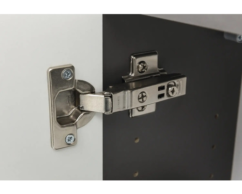 Charnière invisible en métal montée sur une porte d'armoire et un corps de meuble.