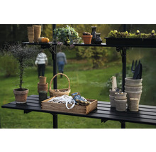 Scène de jardin avec table de plantation, pots, outils et plantes dans une serre