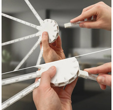 Hände stecken LED-Streifen in einen runden Hub-Verbinder für ein modulares Beleuchtungssystem.
