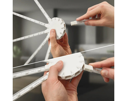 Hände stecken LED-Streifen in einen runden Hub-Verbinder für ein modulares Beleuchtungssystem.