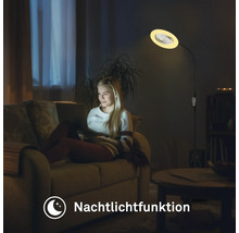 Une femme est assise sur le canapé sous un lampadaire avec fonction veilleuse