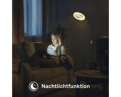 Une femme est assise sur le canapé sous un lampadaire avec fonction veilleuse