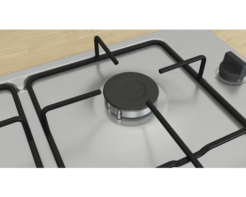 Detailansicht eines Gaskochfelds aus Edelstahl mit schwarzem Brenner und Bedienknopf