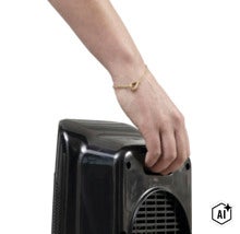 Hand hält einen kompakten elektrischen Heizlüfter am integrierten Tragegriff (Image AI modified or generated)