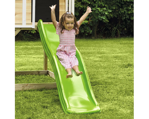 Mädchen rutscht auf einer grünen Kinderrutsche im Garten