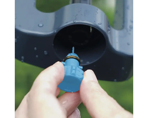 Gros plan d'une main insérant une buse dans un arroseur de pelouse.