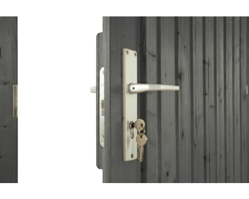 Porte en bois grise avec garniture de poignée en métal argenté et clés dans la serrure.