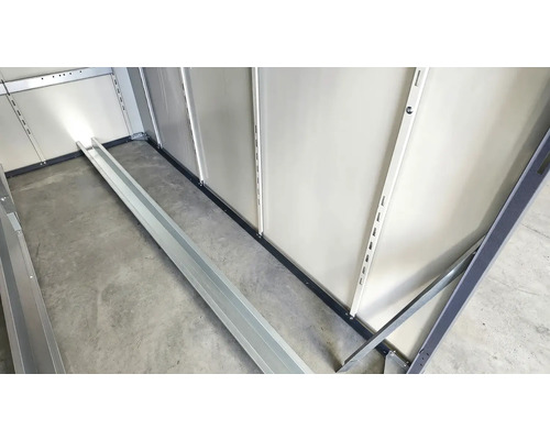 Vue intérieure d'un abri de jardin avec système d'étagères et plinthes.