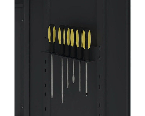 Jeu de tournevis avec manches noirs et jaunes dans un support métallique sur une paroi d'outillage.