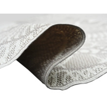 Nahaufnahme eines Flachgewebe-Teppichs mit geometrischem Muster, die Webstruktur und die Rückseite der umgeklappten Ecke zeigt.