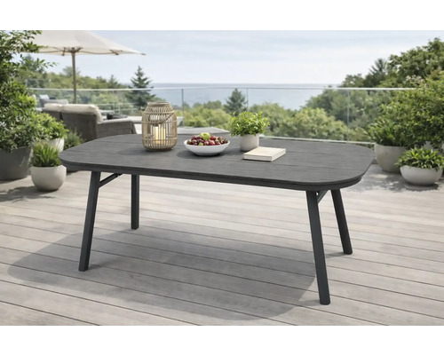 Table de jardin rectangulaire moderne aux coins arrondis sur une terrasse lumineuse et spacieuse. Table gris foncé avec cadre en métal.