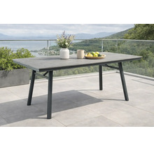 Table de jardin moderne avec plateau aspect bois et cadre en métal sur une terrasse avec rambarde en verre et vue sur le lac et les montagnes.