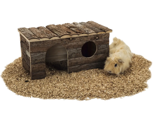 Nagerhaus aus Naturholz mit Rindenbesatz, Rundbogeneingang und Fenster, neben einem Meerschweinchen auf Kleintierstreu.