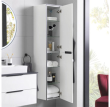 Armoire haute de salle de bain blanche suspendue avec porte ouverte, étagères en verre et articles de toilette dans une salle de bain moderne.