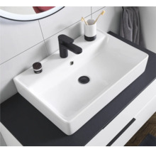 Modernes weißes rechteckiges Aufsatzwaschbecken aus Keramik mit schwarzer Armatur auf einem dunklen Unterschrank im hellen Badezimmer.