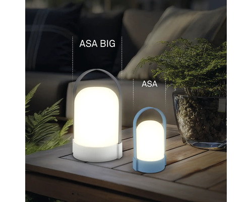 Deux lanternes LED modernes ASA BIG et ASA sur une table en bois, éclairage extérieur chaleureux avec plantes et canapé en arrière-plan.