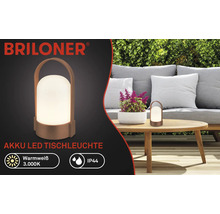 Briloner Logo, lampe de table LED sans fil sur table en bois dans jardin avec canapé et haie, blanc chaud 3000 Kelvin, protection IP44.