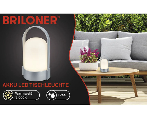 Logo Briloner, lampe de table LED à batterie, blanc chaud 3000 kelvins, IP44, portable avec poignée, dans un jardin sur une table en bois.