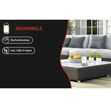 Lampe portable sur une table blanche dans un coin salon lumineux avec meubles en rotin. Caractéristiques : intensité réglable et câble USB-C inclus.