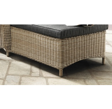 Detailaufnahme eines Gartenmöbels aus Polyrattan mit dunklem Sitzkissen auf Steinboden.