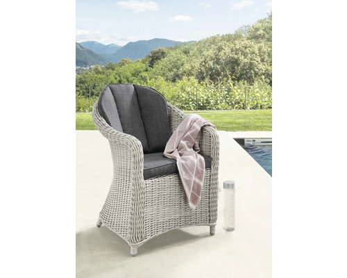 Fauteuil de jardin en polyrotin gris avec coussins foncés sur une terrasse au bord d'une piscine devant un vaste paysage de collines.