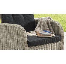 Fauteuil de jardin en résine tressée avec coussins, un plaid à chevrons, un carnet de notes, une photo et un stylo.