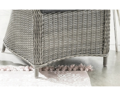 Gros plan sur le piétement d'une chaise de jardin en résine tressée avec coussin.