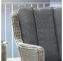 Gros plan sur une chaise de jardin en résine tressée avec coussin gris sur un balcon.