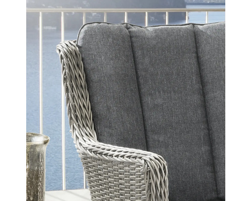 Gros plan sur une chaise de jardin en résine tressée avec coussin gris sur un balcon.