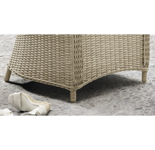 Nahaufnahme eines Gartenmöbels aus Polyrattan-Geflecht mit geflochtenen Füssen auf einem Steinboden.