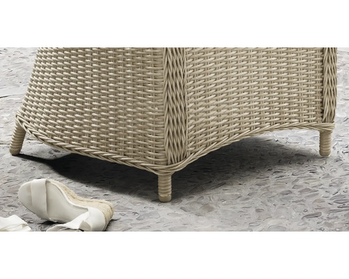 Nahaufnahme eines Gartenmöbels aus Polyrattan-Geflecht mit geflochtenen Füssen auf einem Steinboden.