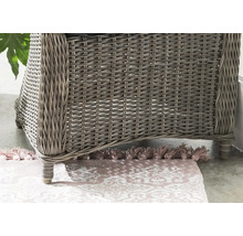 Vue détaillée d'un fauteuil en résine tressée sur un tapis à motifs.