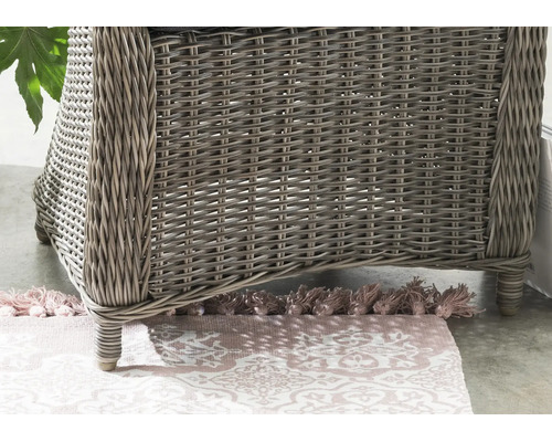 Vue détaillée d'un fauteuil en résine tressée sur un tapis à motifs.