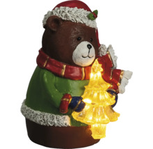Ours brun de Noël avec pull vert, bonnet rouge, écharpe et sapin de Noël illuminé.
