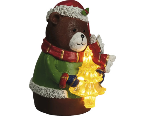 Ours brun de Noël avec pull vert, bonnet rouge, écharpe et sapin de Noël illuminé.