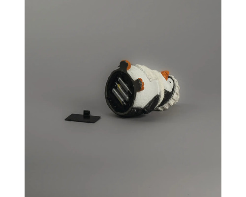 Vue de dessous d'une figurine de décoration pingouin avec compartiment à piles ouvert comprenant les piles et le couvercle.