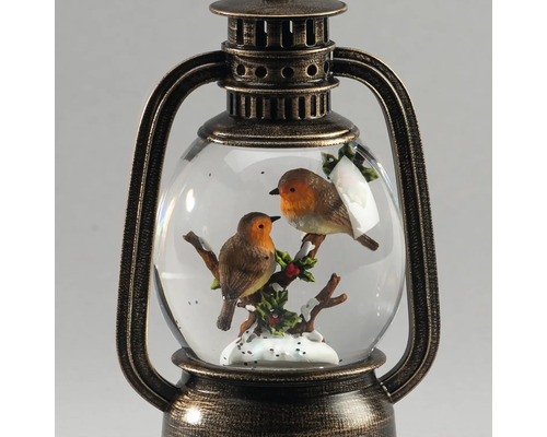 Dekorative Laterne mit Schneekugel, Motiv zwei Rotkehlchen auf einem Ast mit Schnee und Stechpalme, Metallgehäuse in Bronze-Optik.