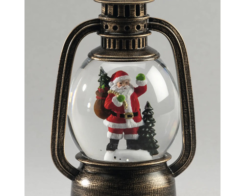 Schneekugel in Form einer antiken Laterne mit Weihnachtsmann-Figur und Tannenbäumen im Inneren.