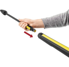 Une main insère une lance de pulvérisation dans un pistolet haute pression, indiqué par une flèche de raccordement.