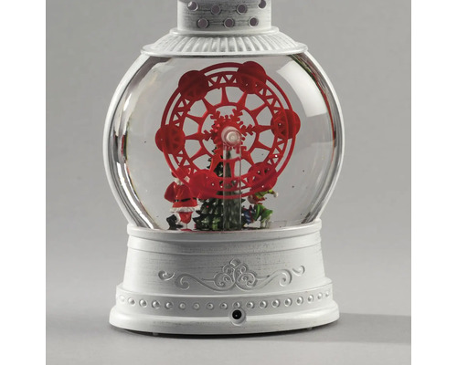 Lanterne boule à neige décorative avec une grande roue rouge, un sapin de Noël et un Père Noël sur un socle blanc orné.
