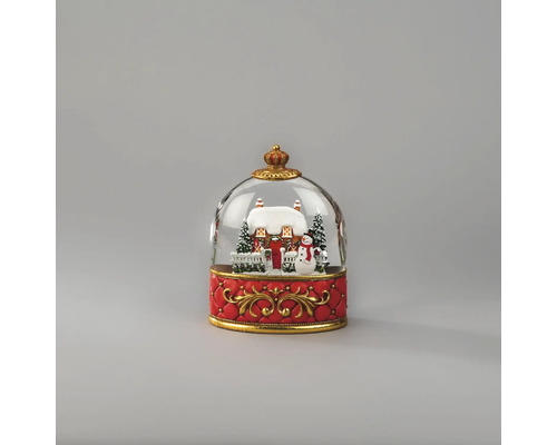 Schneekugel mit verschneitem Haus, Schneemann und Tannenbäumen auf einem verzierten roten Sockel mit goldenen Ornamenten.