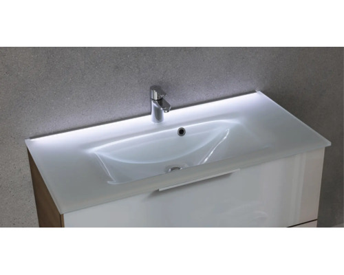 Waschtisch mit weißem Waschbecken, integrierter LED-Beleuchtung an der Rückseite, verchromter Armatur und weißem Unterschrank.