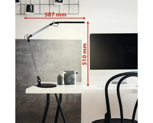 LED Schreibtischlampe auf hellem Schreibtisch neben Monitor und Kamera. Maße: 587 Millimeter Breite und 510 Millimeter Höhe.